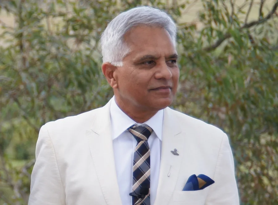 Dr Jonathan Toussaint in a white suit at a ceremony
